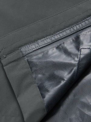 Close-up texture of dark grey waterproof lightweight rain jacket with hood fabric showing water-repellent weave detail.