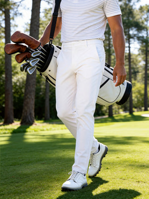 Outdoor shot of a model holding a golf bag, wearing the white soft lightweight casual golf pants with 5 pockets for active play