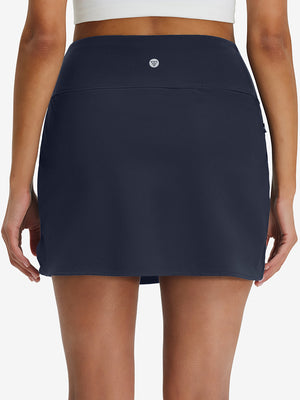 Back lower body shot of model wearing navy high waist built-in short a-line golf skirt with 5 pockets