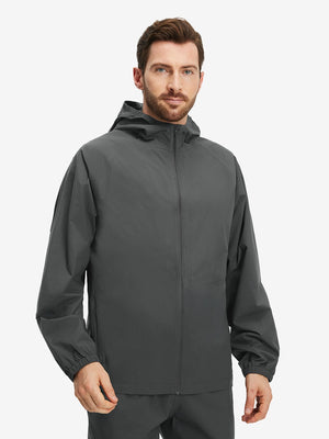 Front upper body shot of model wearing dark grey waterproof lightweight rain jacket with hood