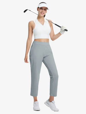 Full-body front view wearing golf hat and holding club in LIGHT GREY Women's 7/8 Ankle Golf Track Pants.