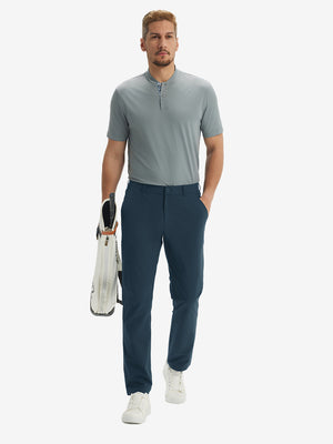 Full-body front: model in navy stretch quick dry casual golf pants with 4 pockets carrying golf bag by hand.
