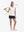 Front full body with golf club in white of women's 4 buttons golf polo shirts.