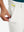 Hand placing a golf ball into pocket of water-resistant golf stretch nylon pants in white.