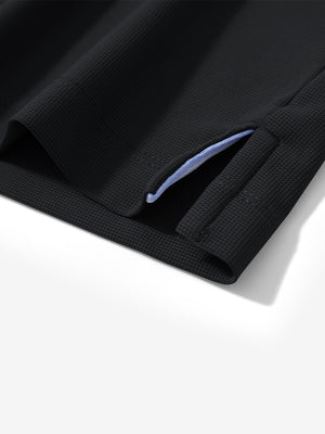 Detail view of hem on black dry fit waffle textured collared golf shirts