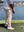 A model wearing light khaki water resistant everyday pants plays golf on the golf course
