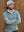 Model with hands clasped by a wooden wall, wearing moisture wicking quarter zip pullover in dark green melange