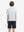 Back half-body view of youth wearing white golf performance print boys golf polo, showing rear design